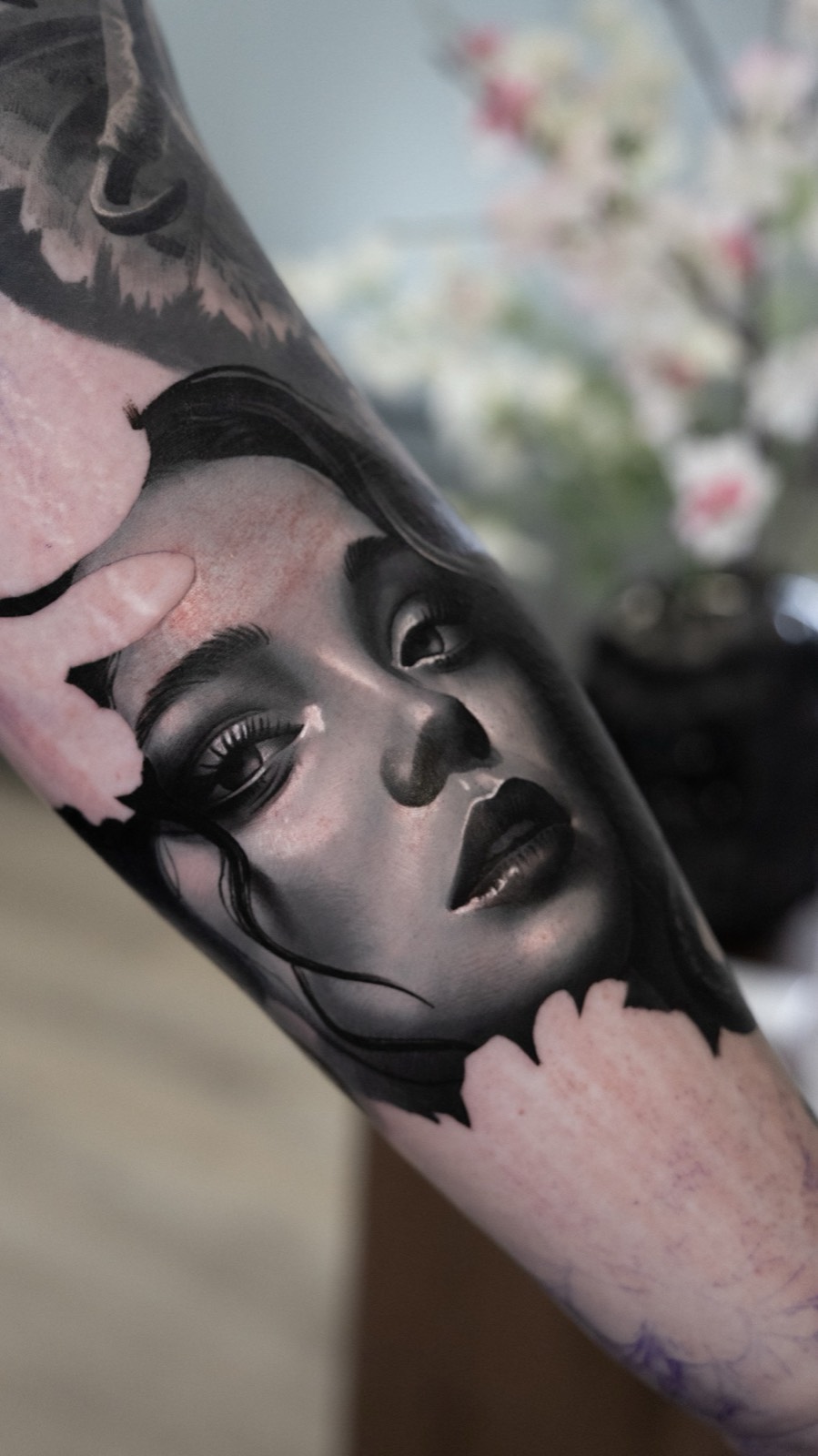 Realistic black and grey female portrait framed by flowers
