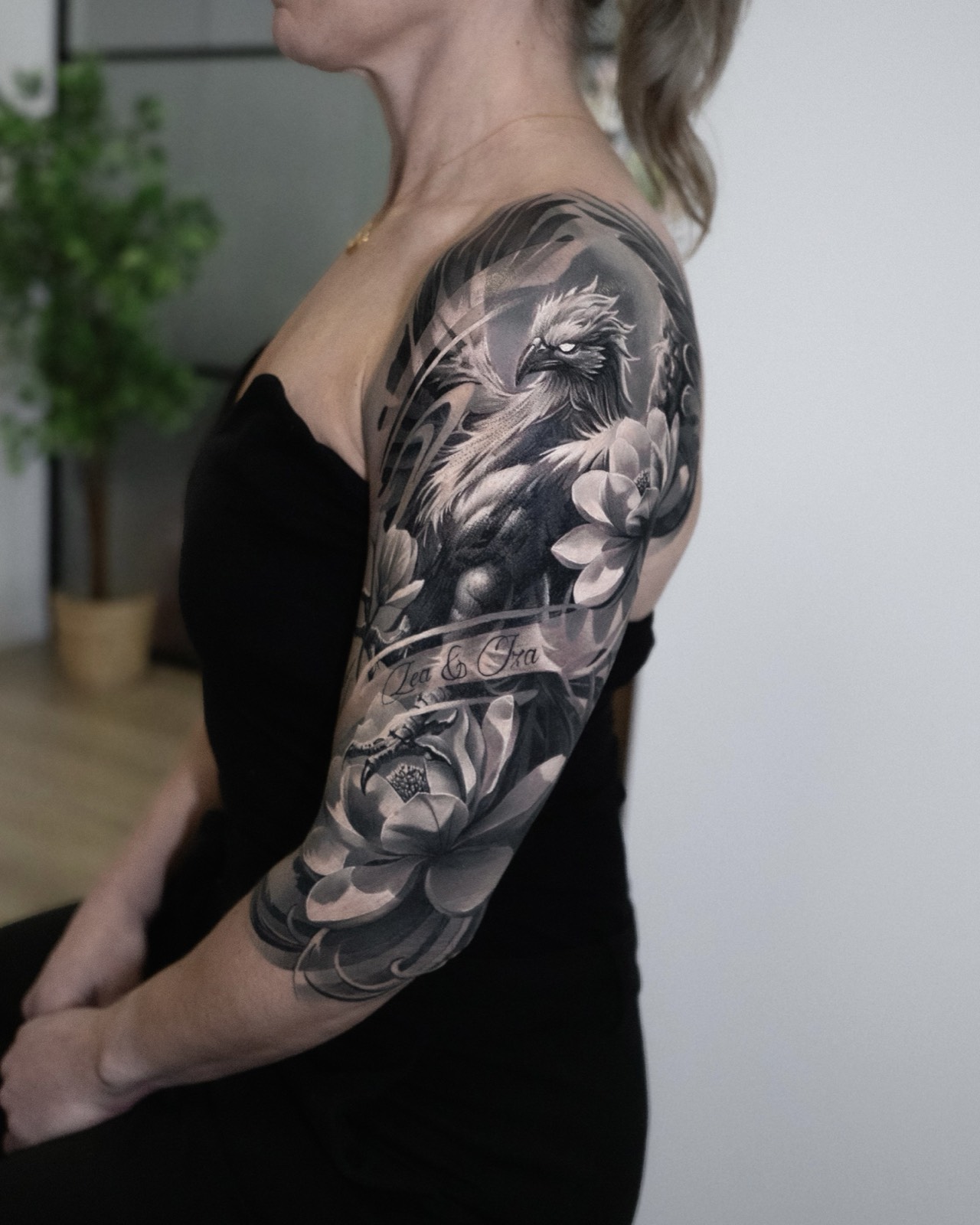 Black and grey phoenix and lotus upper-arm tattoo